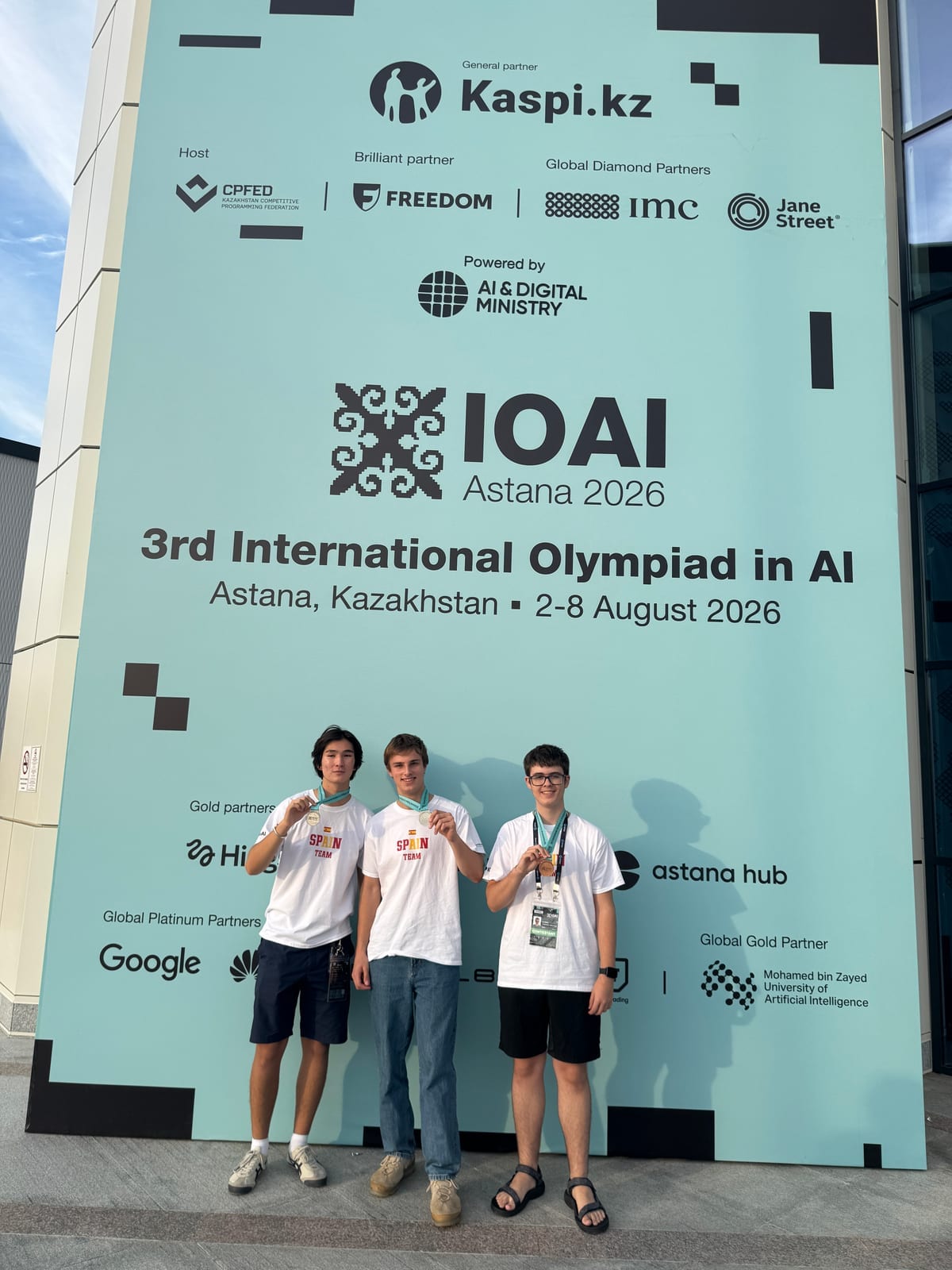 Medallistas ante el cartel de la IOAI Astaná 2026.